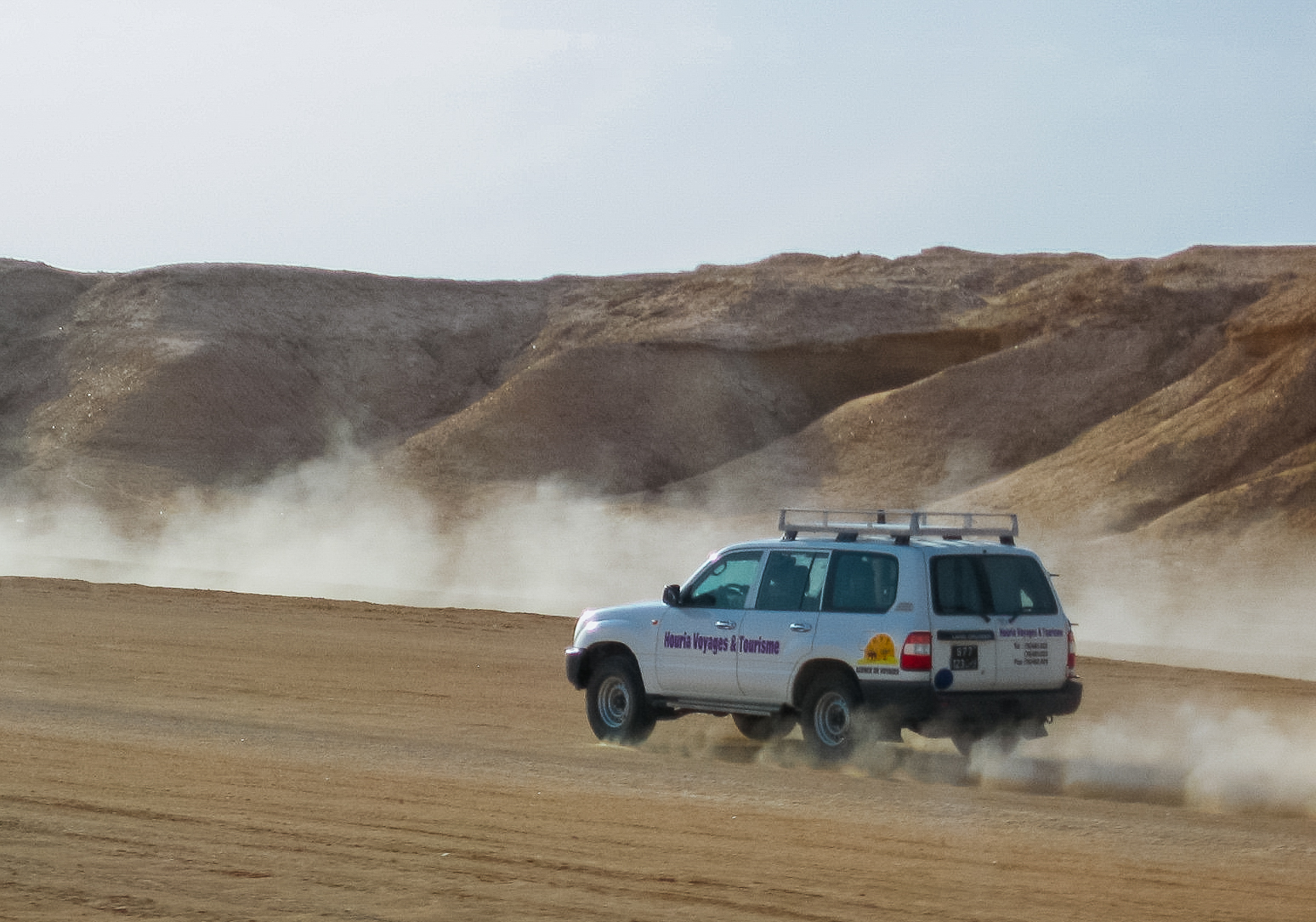 Off-road vehicle riding a sand dune.